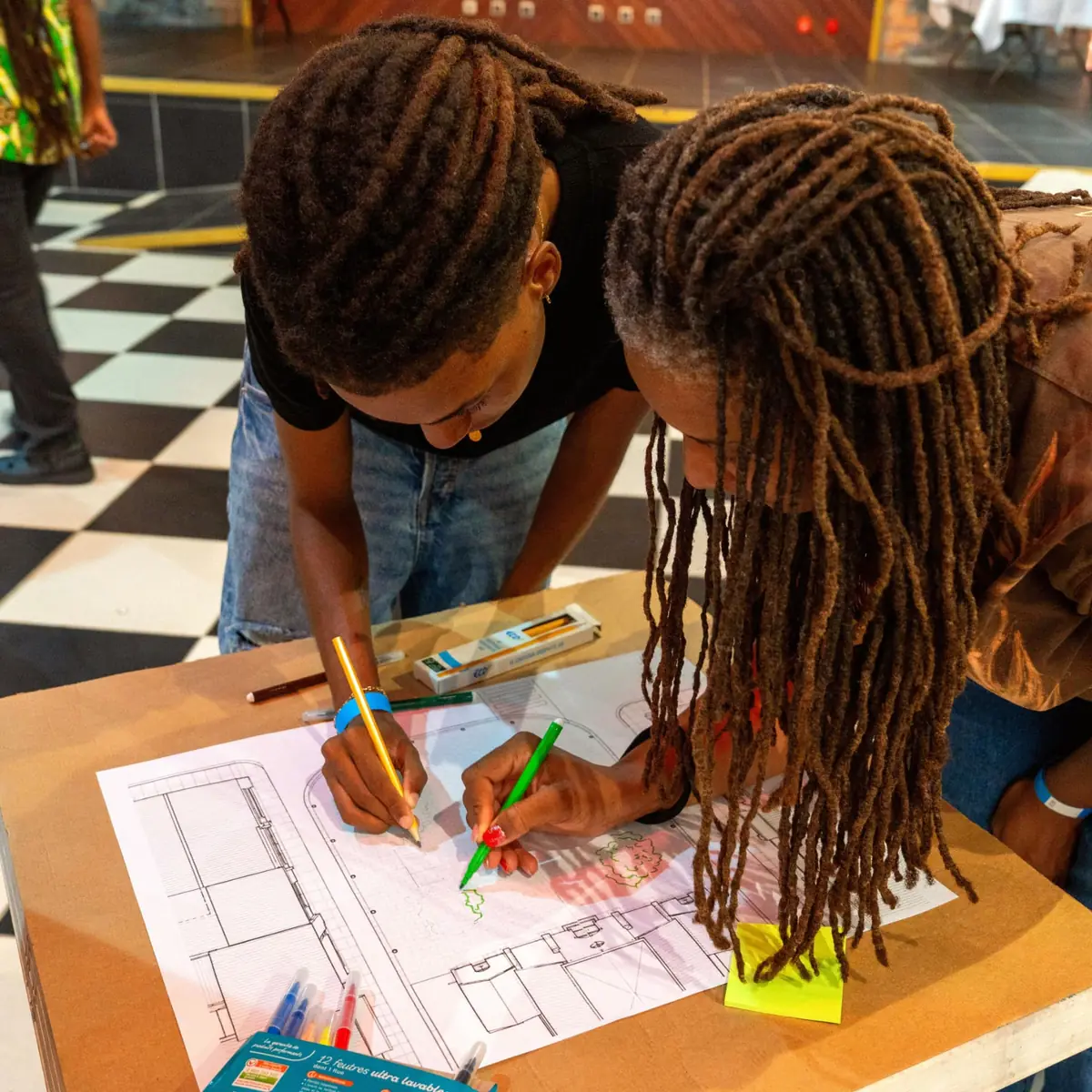 Une mère et son fils dessinant ensemble sur une feuille pendant un atelier du Salon du Design en Martinique